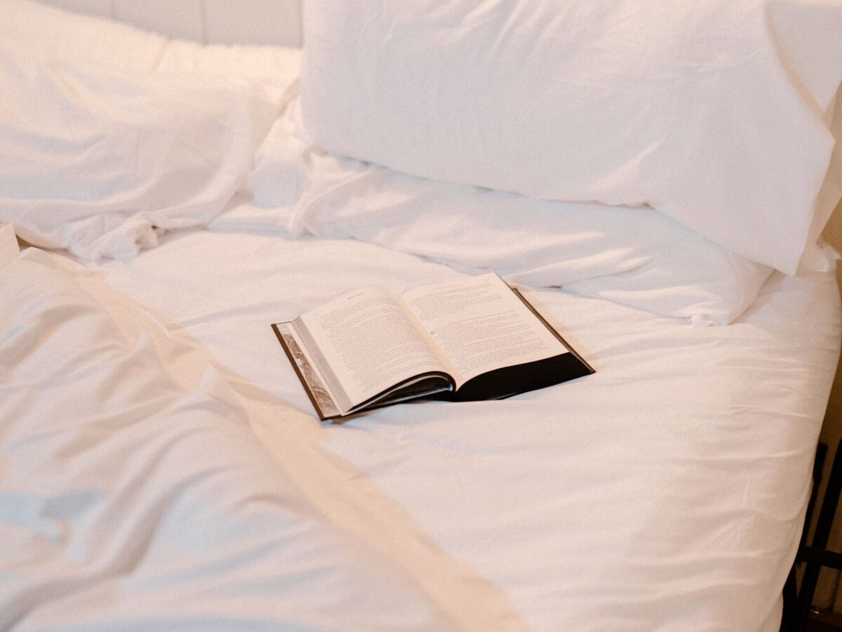 King bed made up with white linens and a book in the main bedroom of the cabin