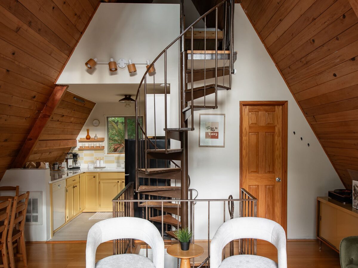 The upstairs loft bedroom with twin beds tucked under the A-frame ceiling beside the spiral staircase