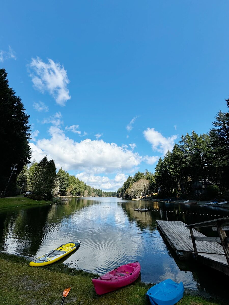 Kayaks and paddle boards pulled up on the shoreline of Lake Minterwood on a clear summer day