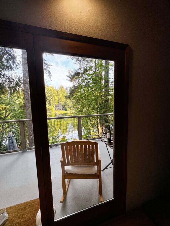A chair on the balcony framed by the doorway, with the lake beyond
