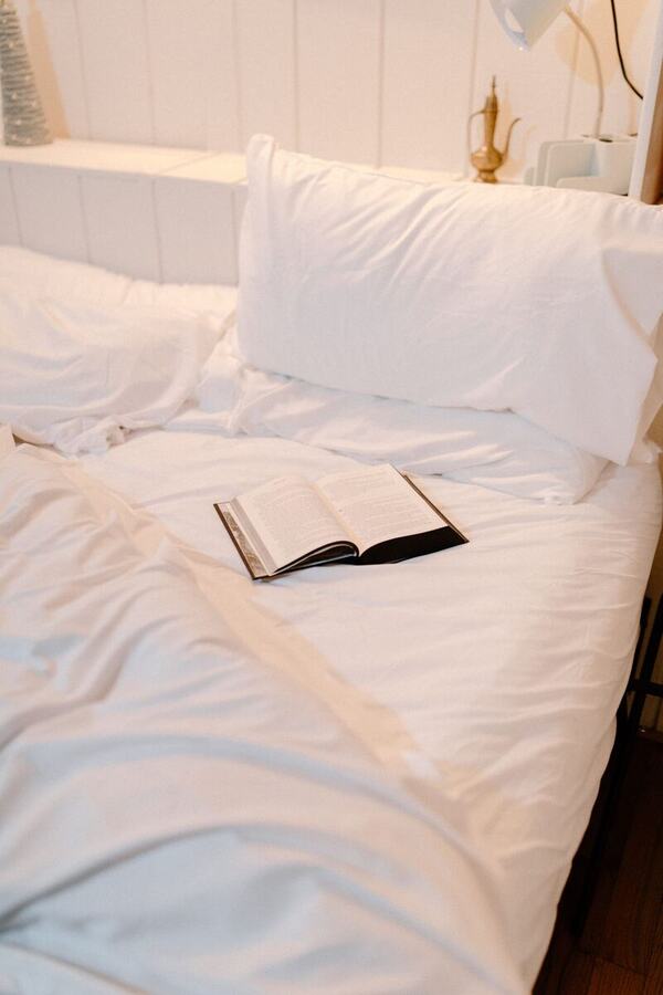 The main bed made up in white linens with a book left open on the duvet