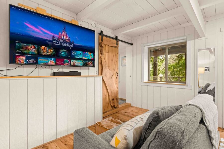 The lounge area off bedroom one with a wall-mounted TV, sofa and barn door