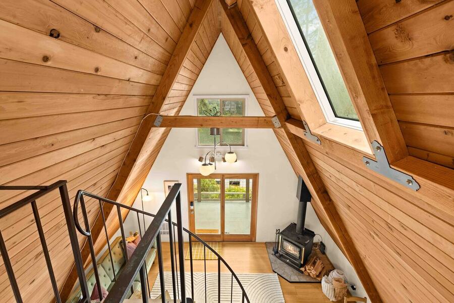 The view down from the loft over the railing to the living room and wood stove