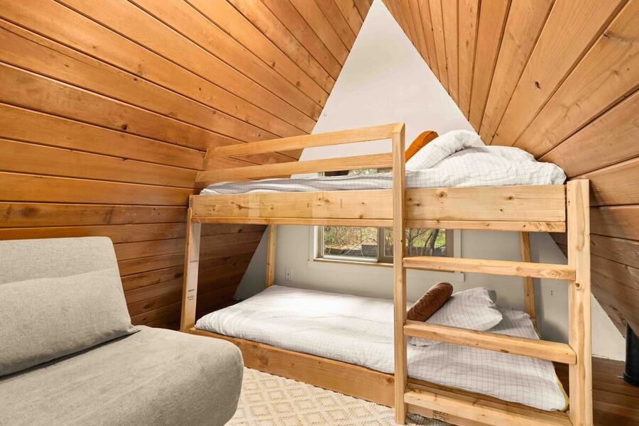 The wooden bunk beds in the loft under the cedar A-frame ceiling