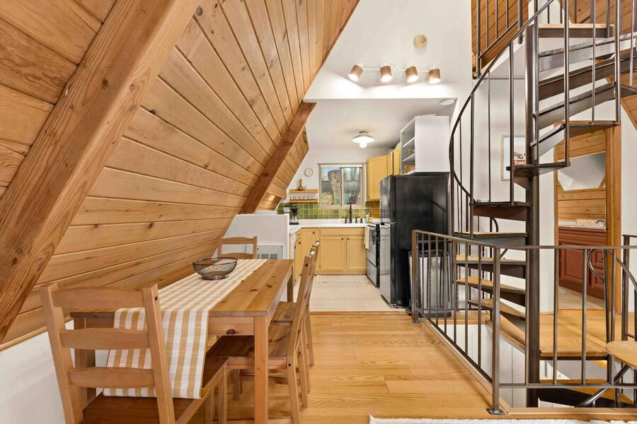 The dining table and chairs on the main level next to the spiral staircase and kitchen