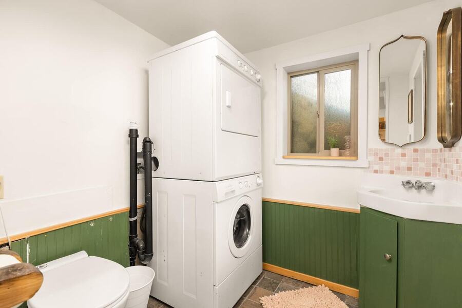 The half bath with a green vanity, arched mirror and the stacked washer and dryer