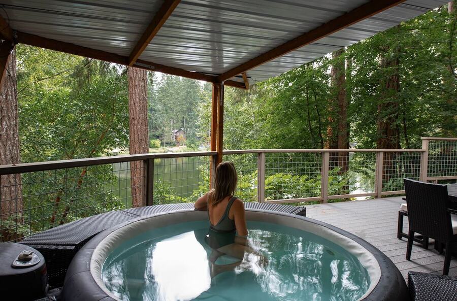 Soaking in the hot tub under the covered deck with the lake and trees beyond