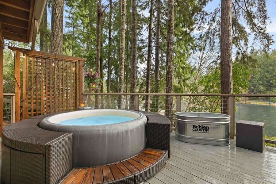 The hot tub on the cedar deck with a privacy screen and fir trees
