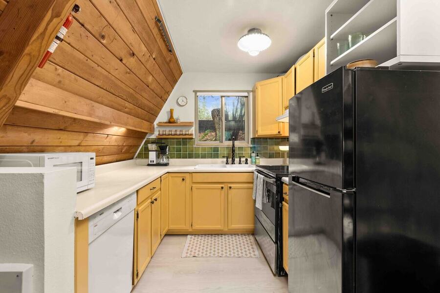 The full kitchen with wood cabinets, a full-size range, refrigerator and dishwasher