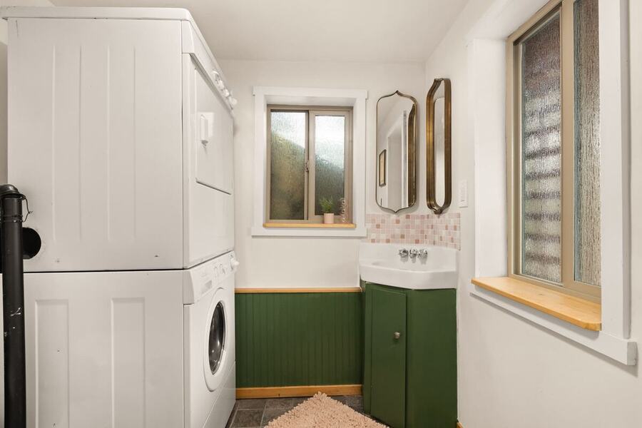 The stacked washer and dryer beside the green vanity in the laundry