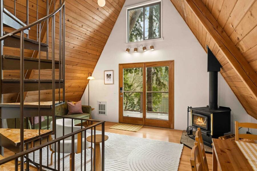 Looking across the main level from the spiral staircase to the wood stove and the glass doors facing the lake