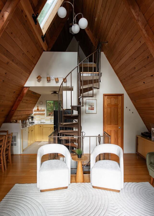 The full height of the A-frame ceiling with the skylight, spiral staircase and dining table below