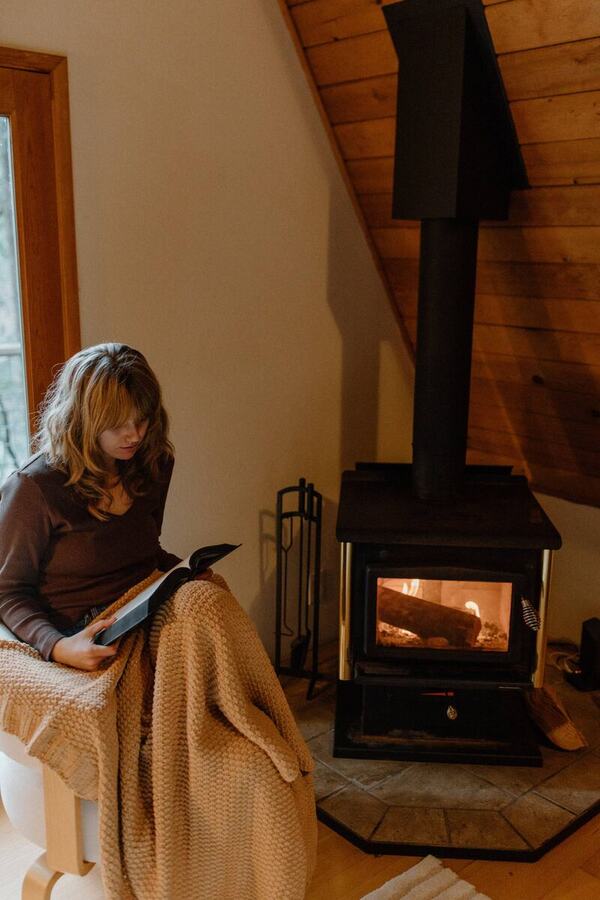 Reading in an armchair next to the lit wood stove on a cool afternoon
