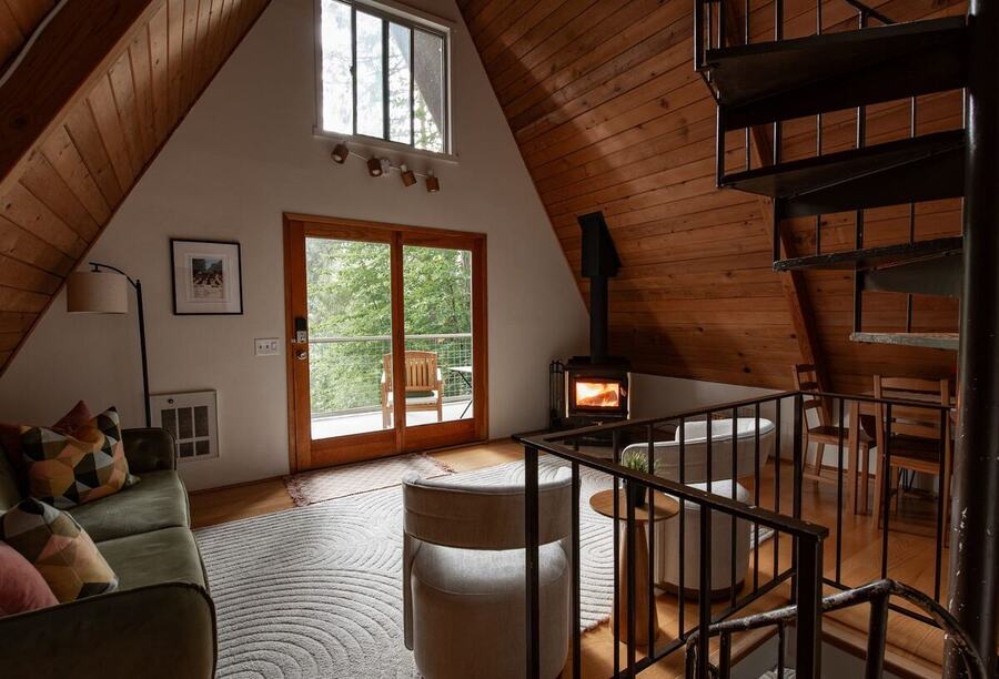 Wide view of the main living area with the sofa, wood stove and spiral staircase