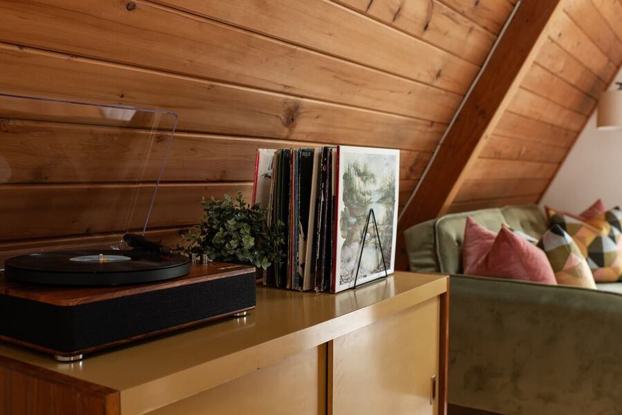 The record player and vinyl collection on the console behind the sofa