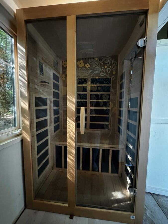 The two-person infrared sauna with its glass door and cedar interior