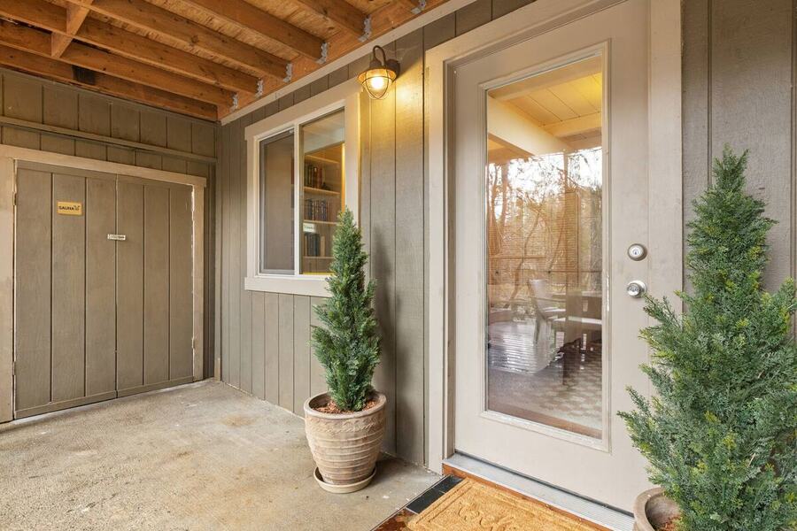The covered entry with lights and potted plants at the cabin door